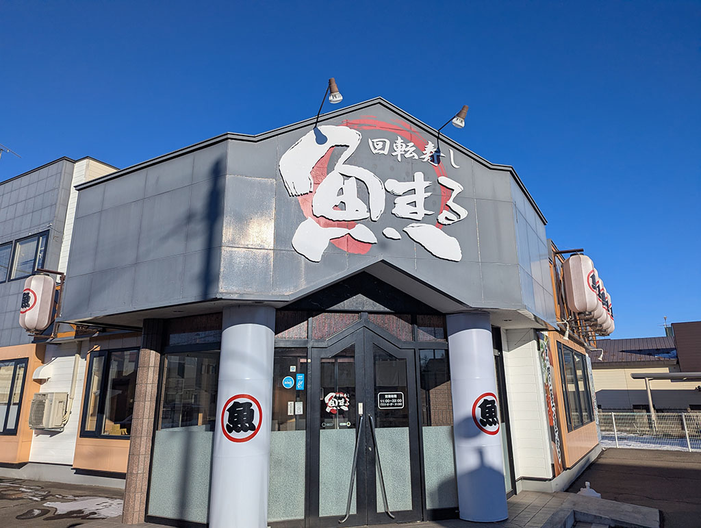 帯広の回転寿し魚まるの店舗外観。青空の下に大きな看板が目立つ