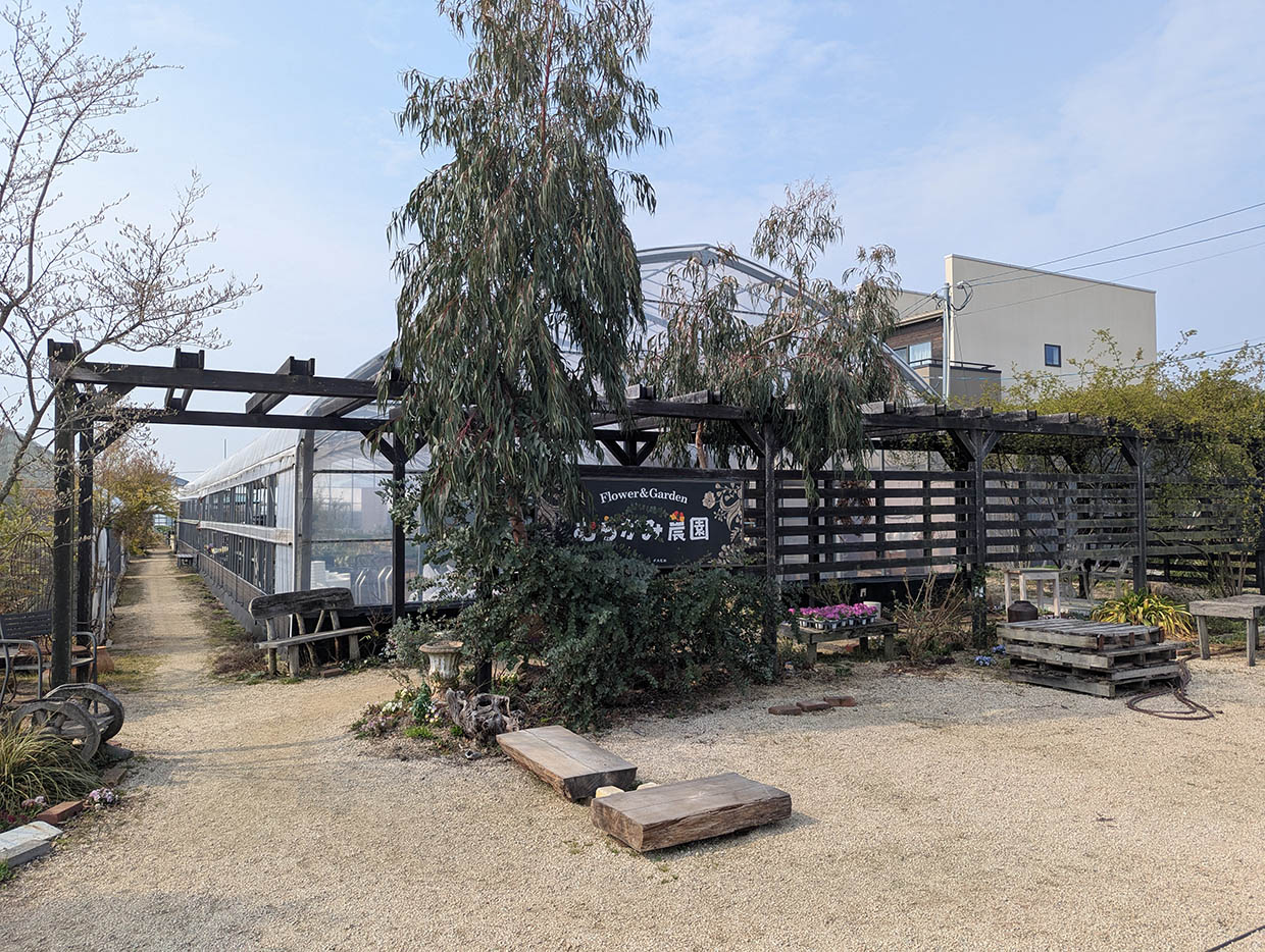 むらかみ農園の温室とガーデン入り口のウッドアーチと植栽