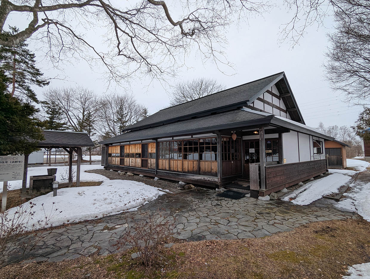雪の残る庭に建つ、開拓記念館の木造和風建築