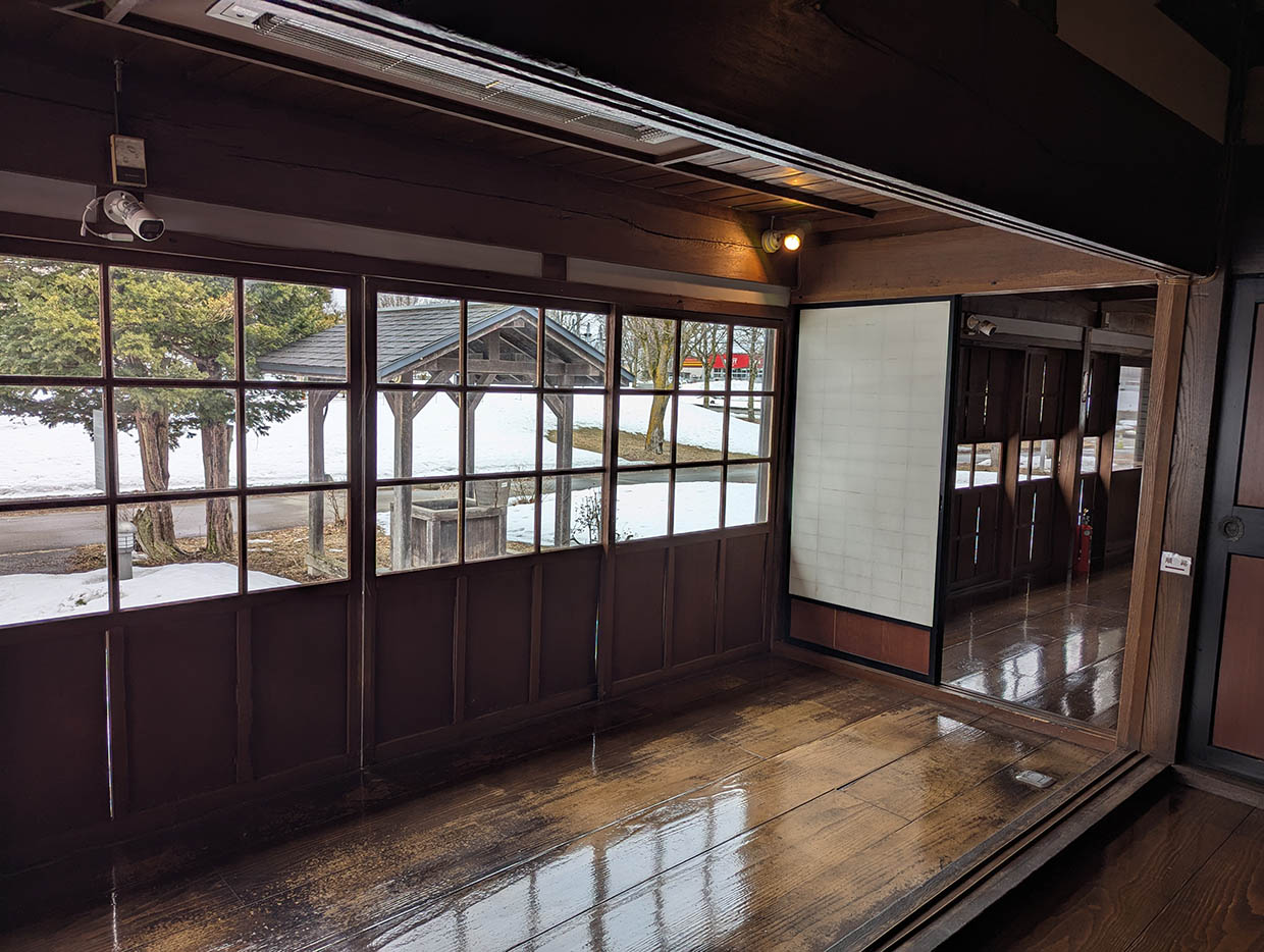 記念館の縁側から外を望む風景。雪景色と古い木枠窓が重なって見える。