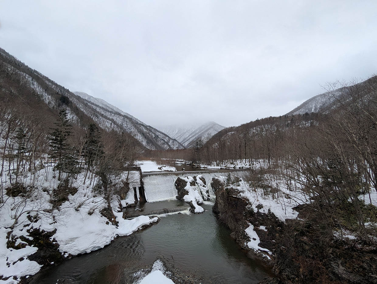 雪に覆われた山々と渓谷に流れ落ちるピョウタンの滝