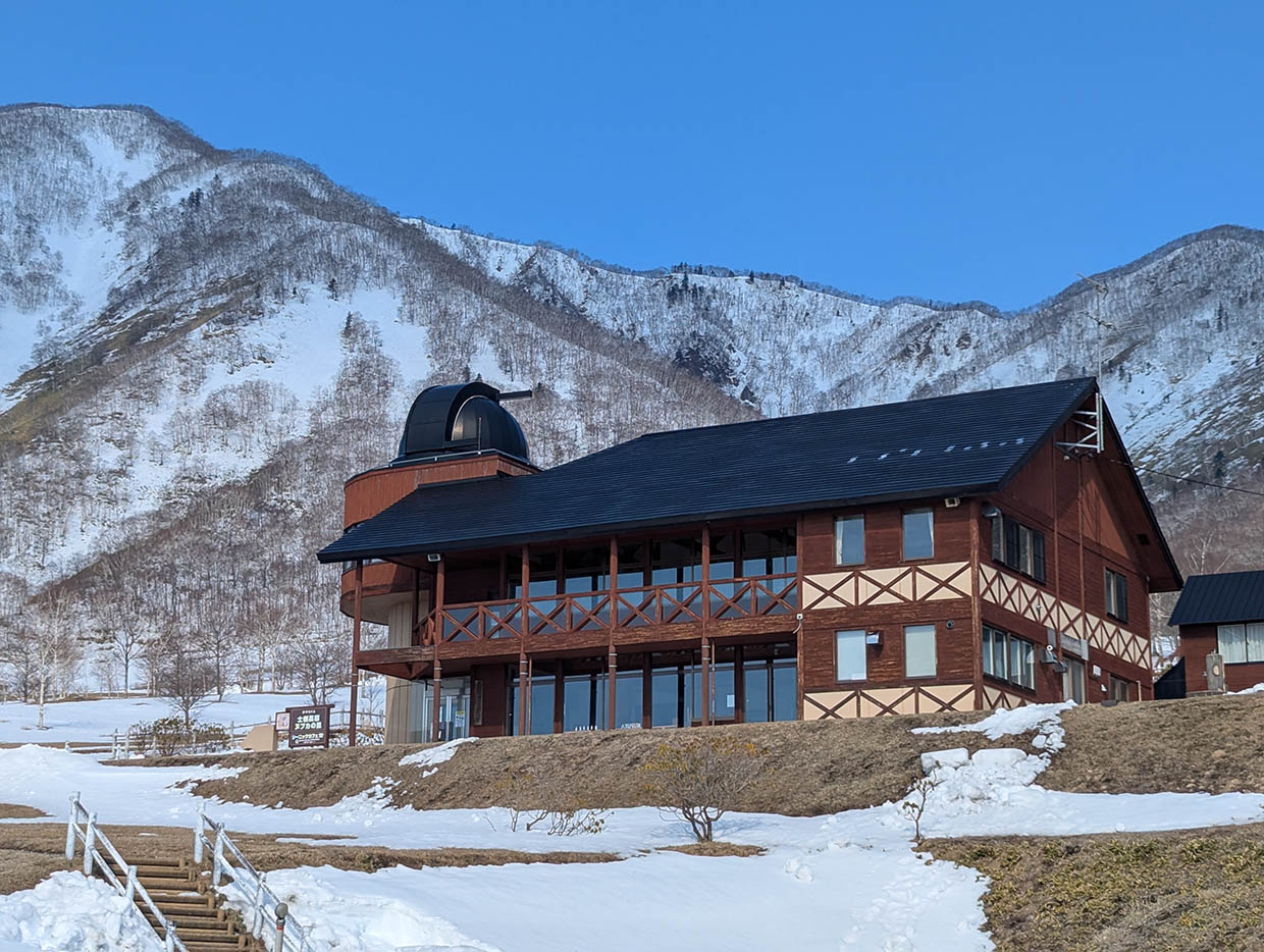 ヌプカの里の木造ロッジと背景にそびえる雪山