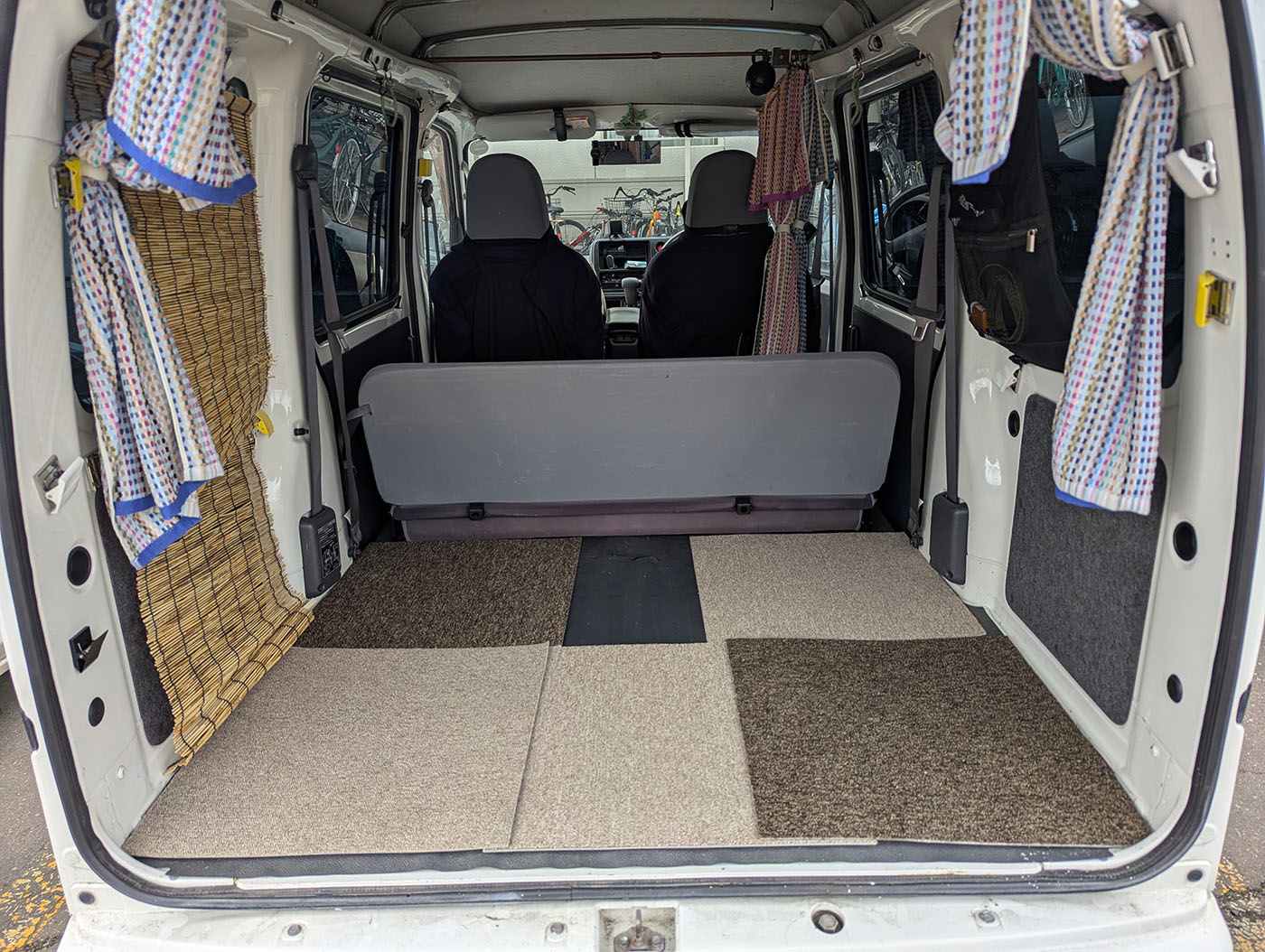 車中泊仕様の軽バン後部にカーペットを敷いた状態。フラットな床に複数のカーペットが敷かれ、快適さがアップしている車内。