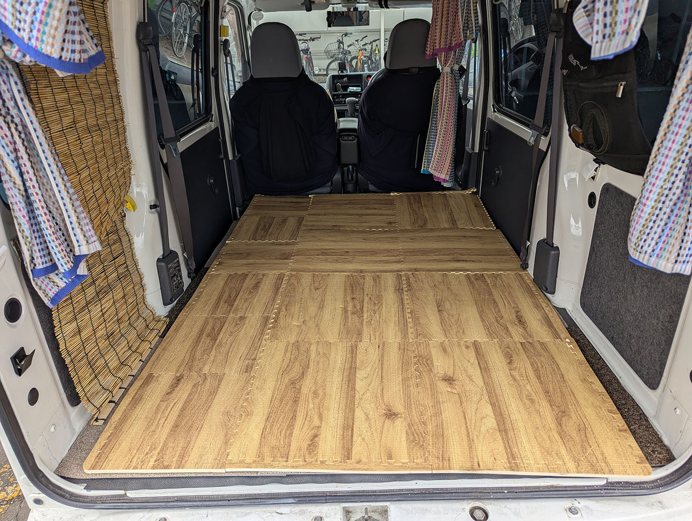 車中泊仕様の軽バン後部に木目調のジョイントマットを敷き詰めた状態。床が明るく暖かみのある雰囲気になっている。