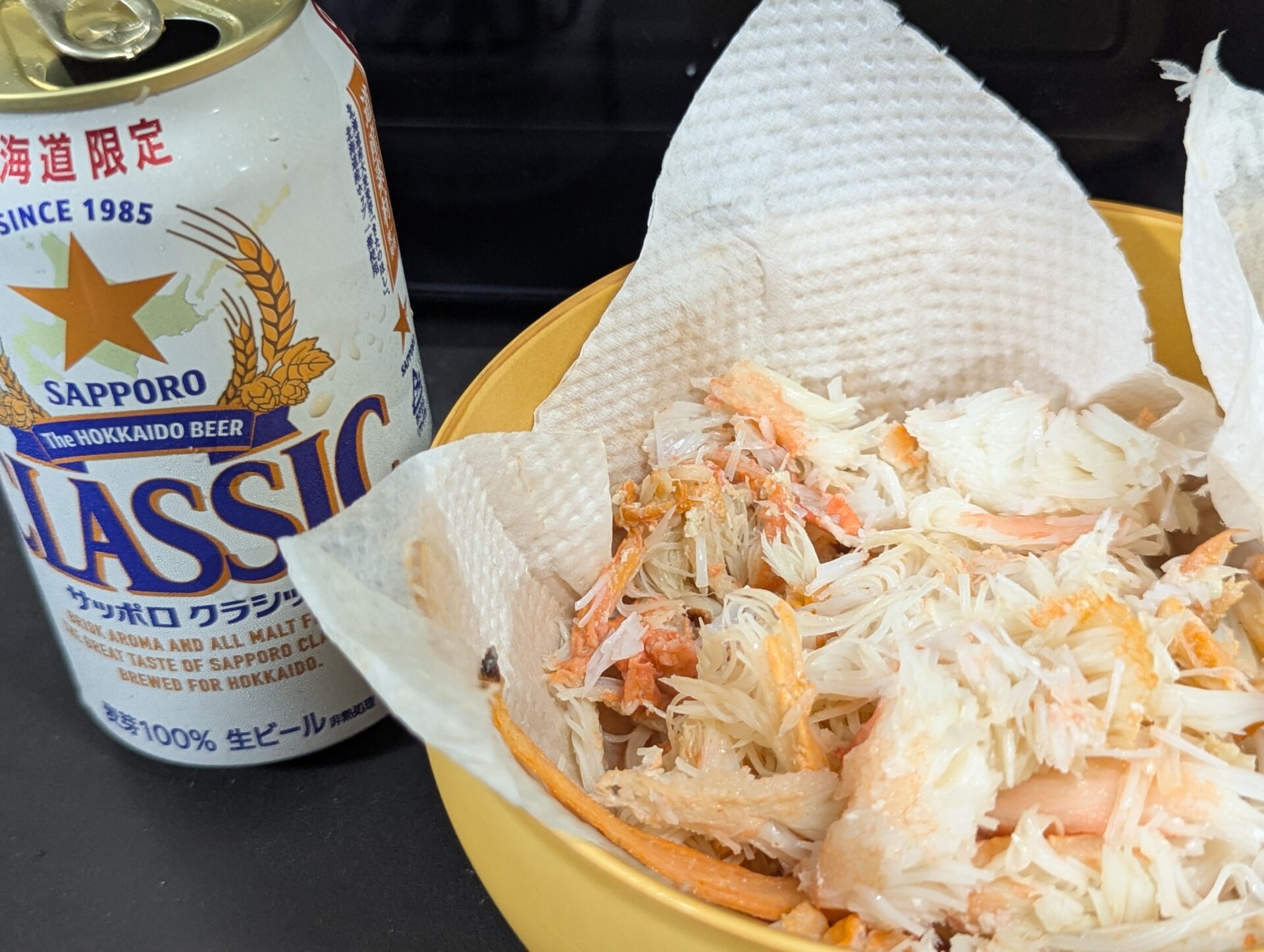 キッチンペーパーの上にほぐしたズワイガニの身と、北海道限定のサッポロクラシックビール。