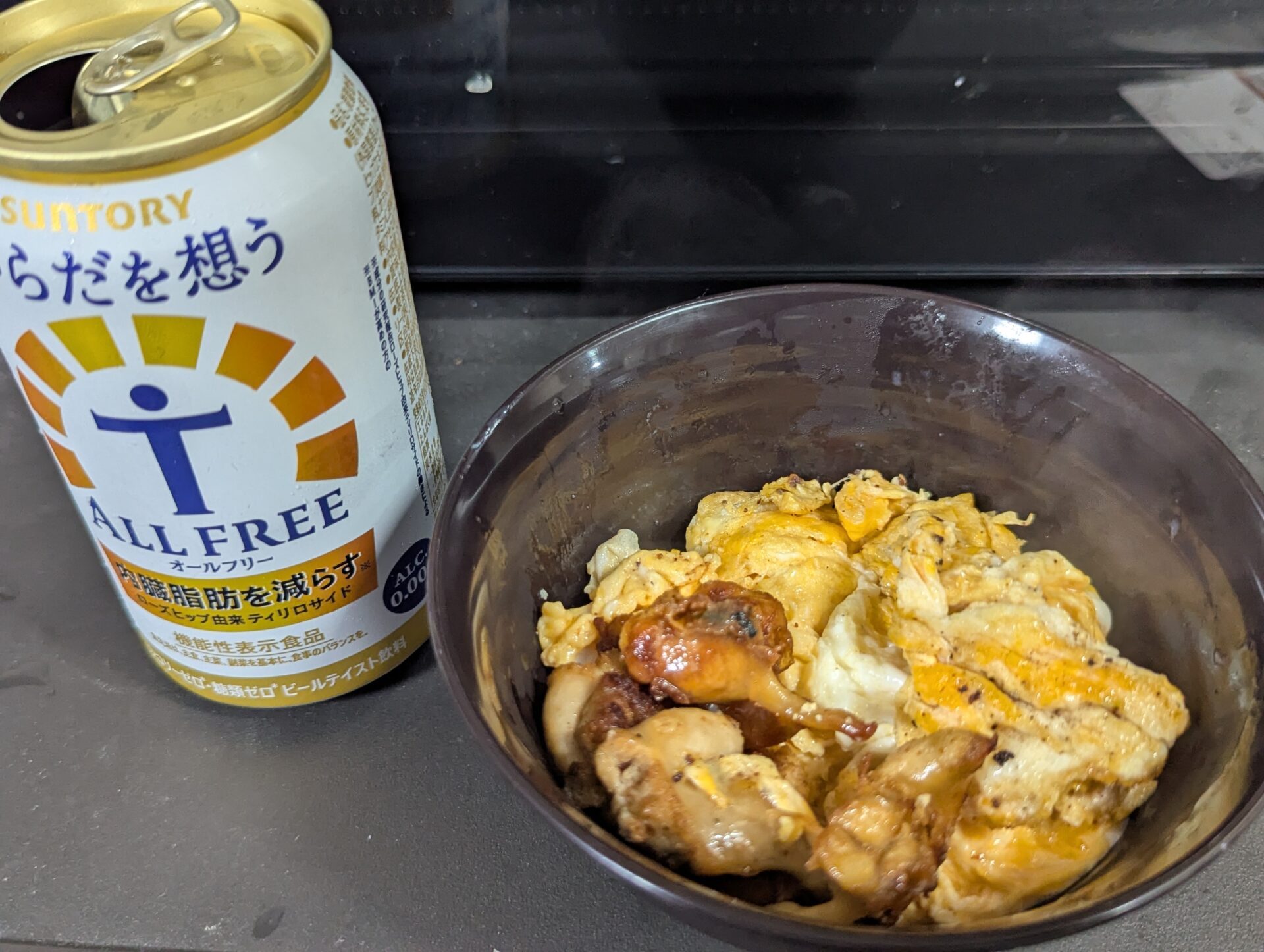 ホタテ子の卵とじ丼と、サントリー「オールフリー」の缶。旅先の晩酌セットのような一品。
