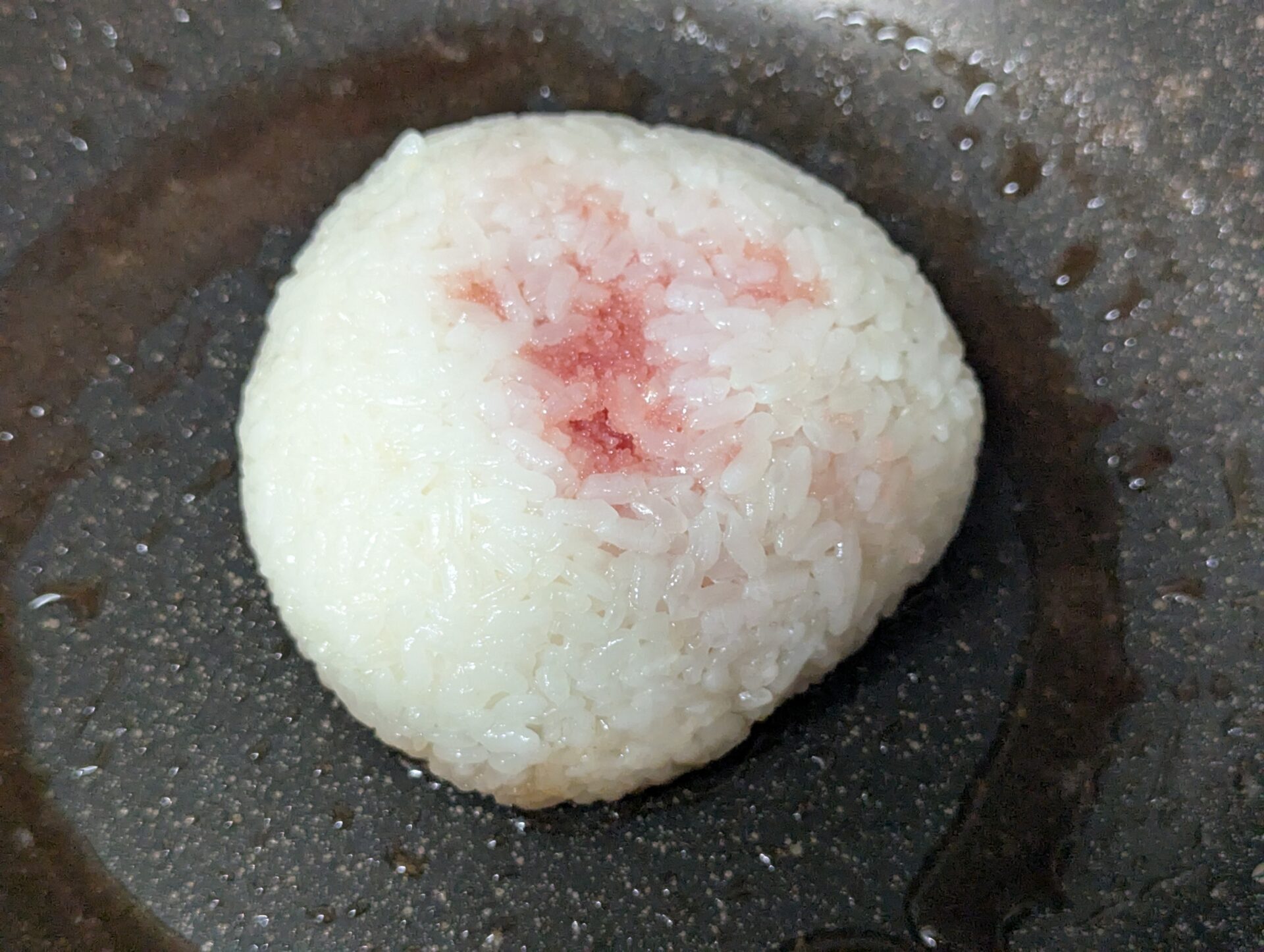 もち米で握ったおにぎり。中央に赤いたらこがのぞいており、じんわりと味が染みていく。