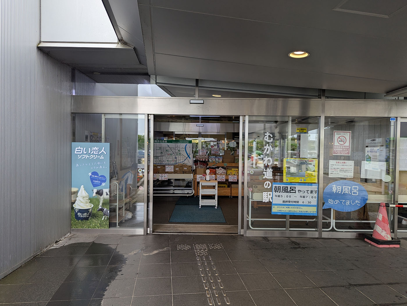 道の駅むかわの正面入口の写真。自動ドアには「むかわ道の駅」と書かれ、営業時間案内やソフトクリームの看板が並び、施設の雰囲気がわかる。