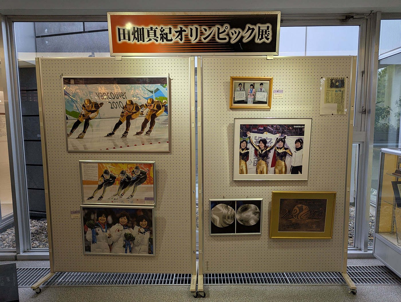 「田畑真紀オリンピック展」と題されたパネル展示。バンクーバーオリンピックでのスピードスケートの活躍やメダル授与の写真が額装されている。