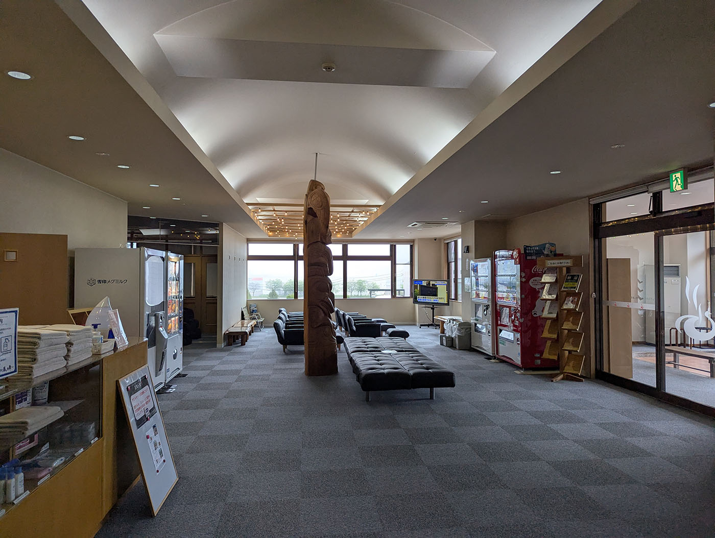 鳳乃舞温泉の広々としたロビー。自販機やソファが並び、中央には木彫りのオブジェが設置されている。