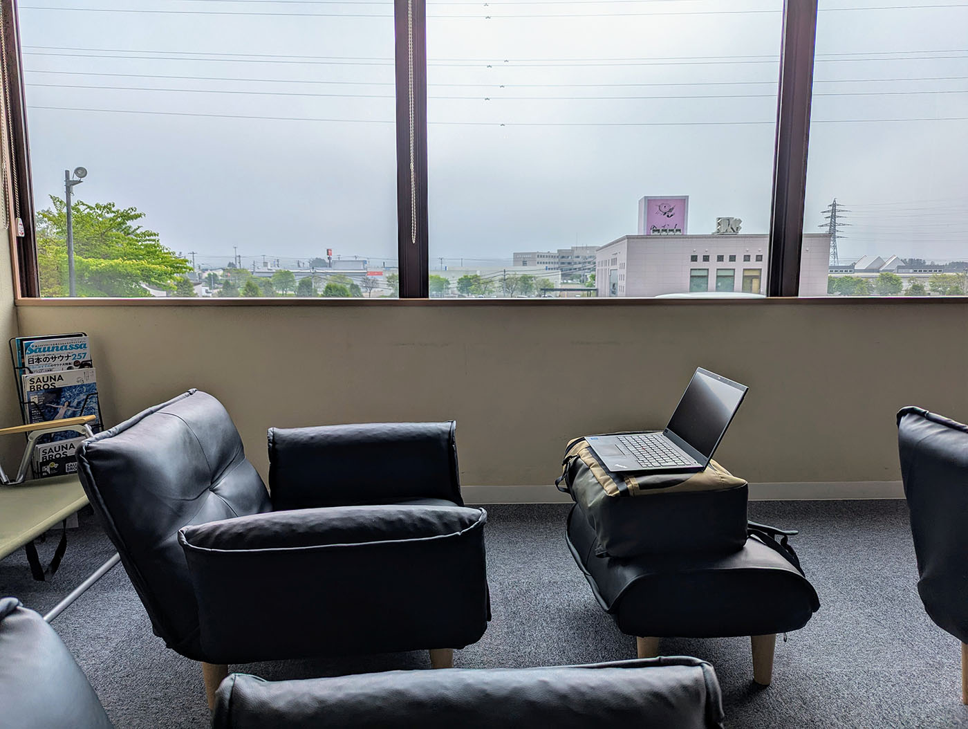 鳳乃舞温泉の館内、窓際のソファスペースに設置されたノートパソコン。外には十勝の町並みが広がる。