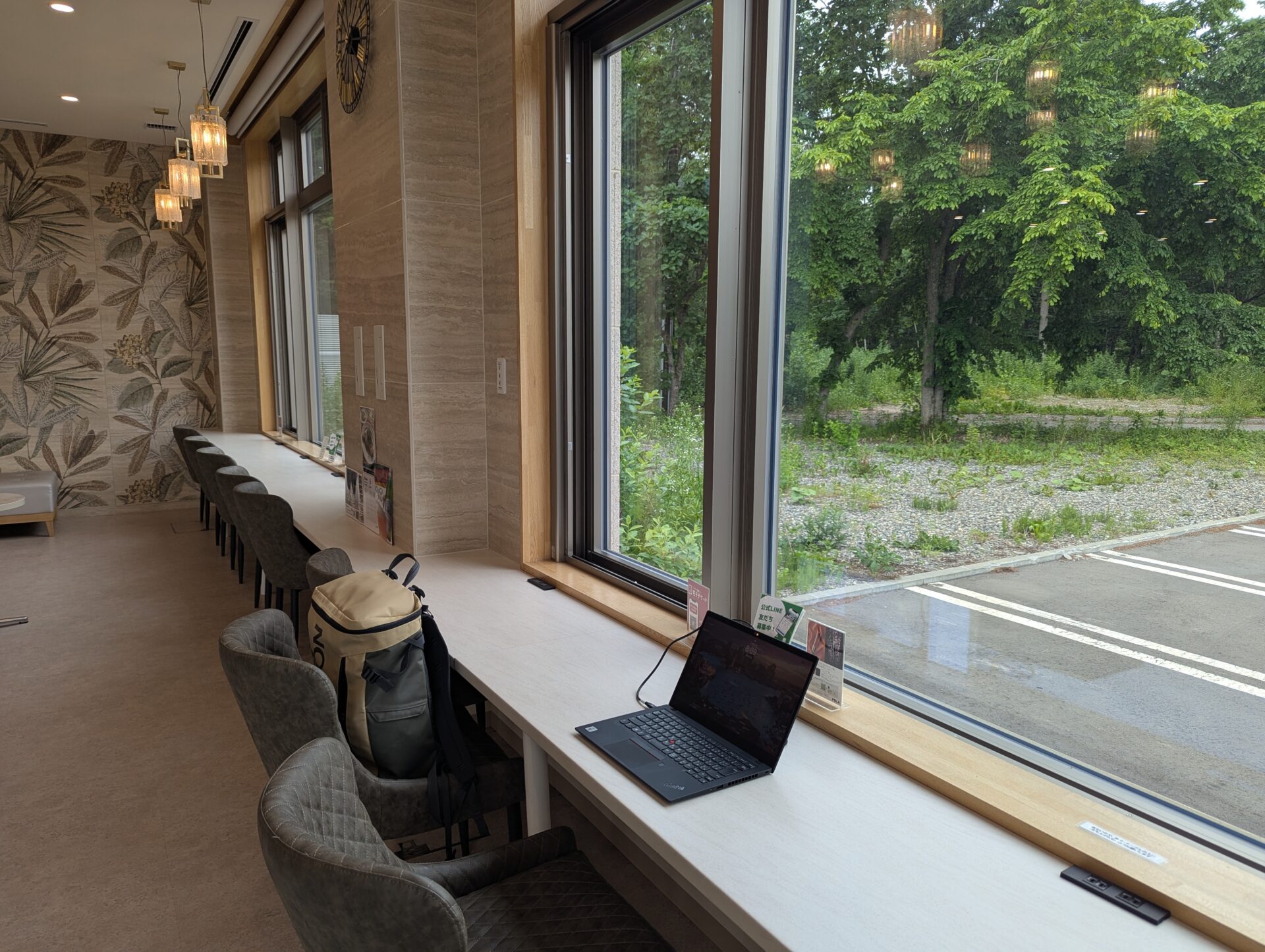 十勝エアポートスパそらの休憩所、窓際のテーブル席にノートパソコンとリュックが置かれている