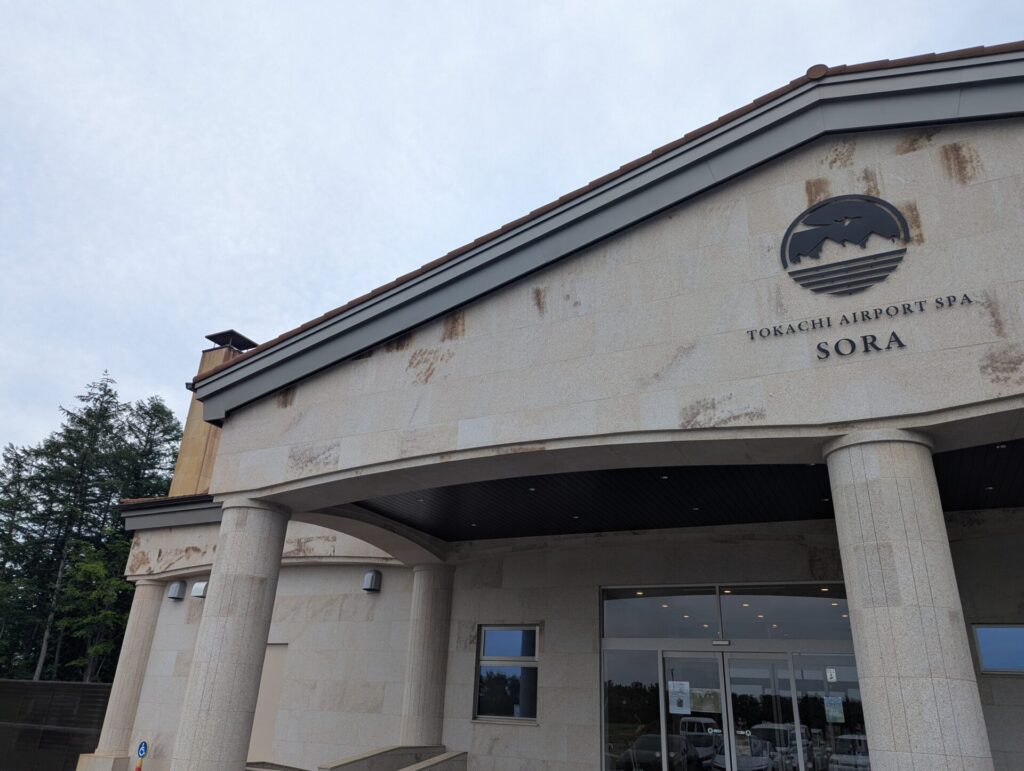 十勝エアポートスパそらの外観、入口とロゴが見える石造りの建物