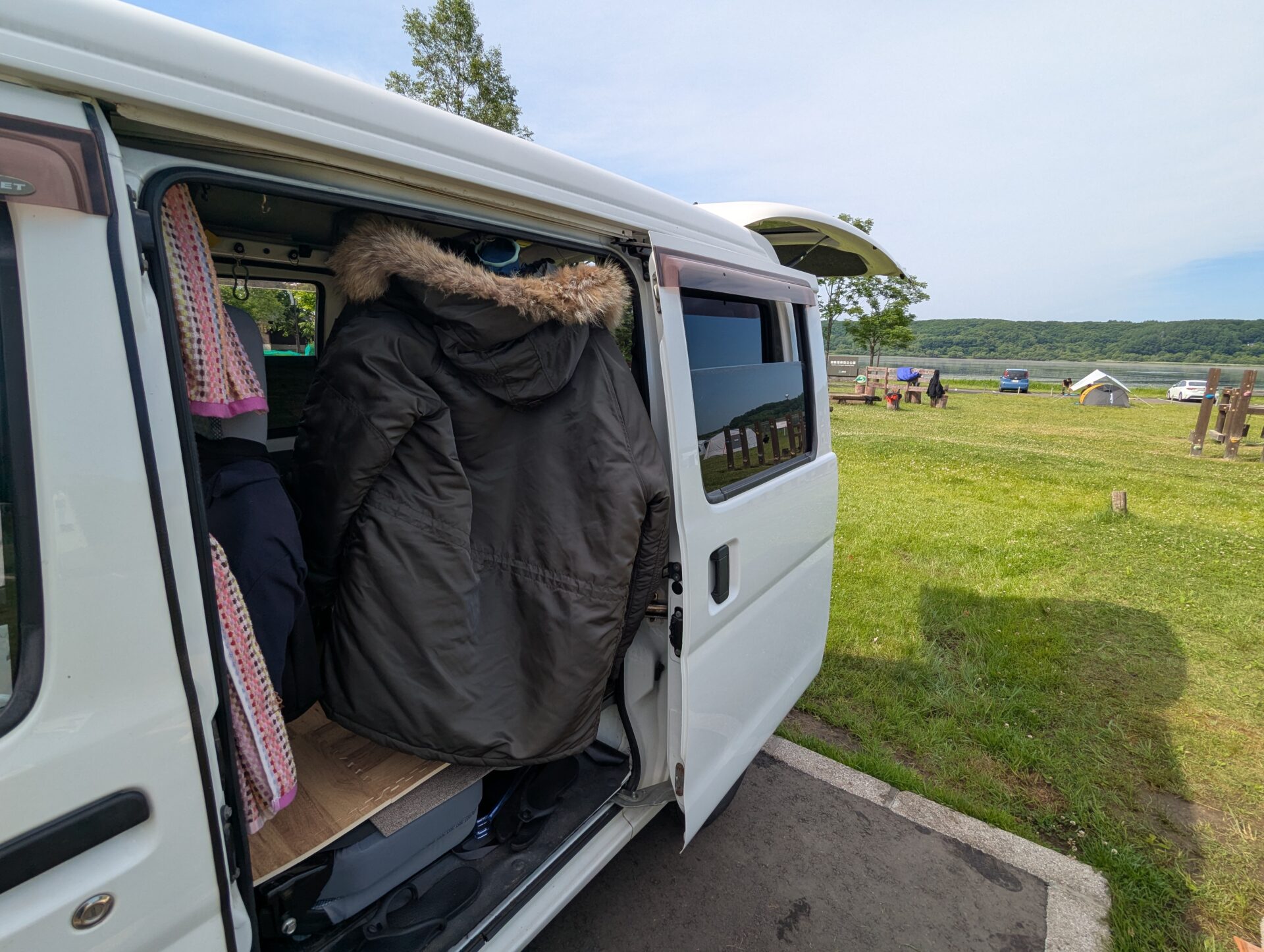 キャンプ場で後部ドアを開けた車の中に掛けられた冬用ジャケット