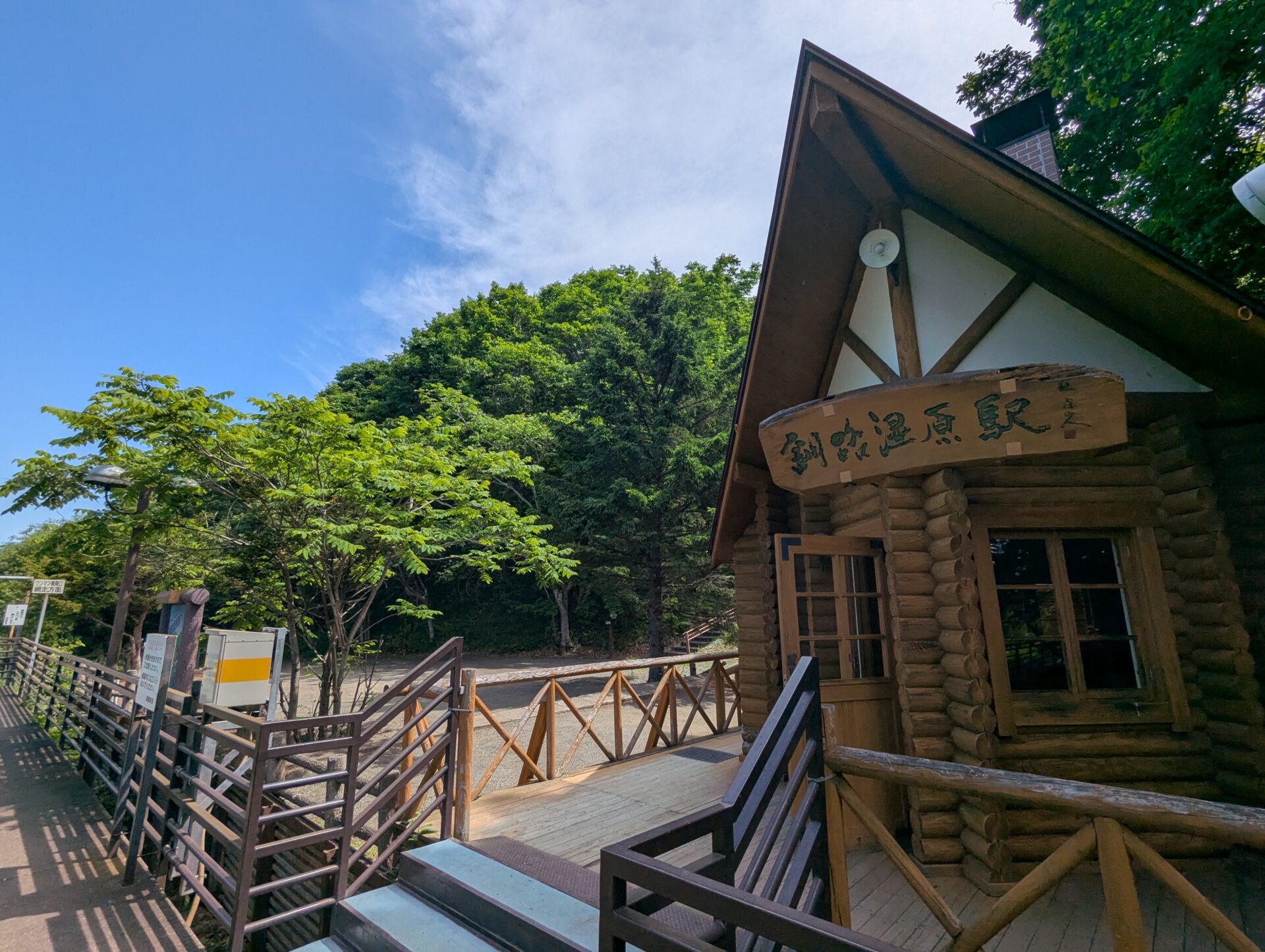 青空の下、森に囲まれた木造の釧路湿原駅舎
