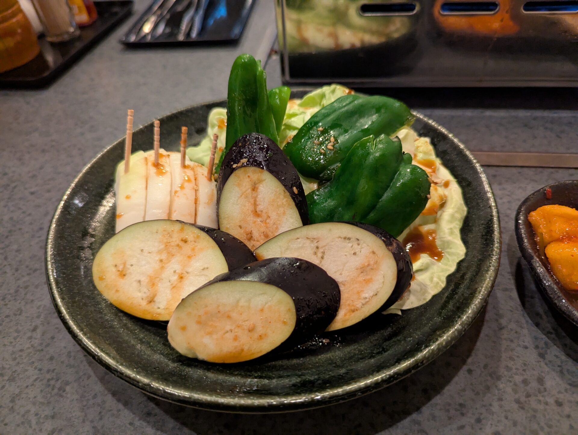 焼肉まるよしで提供された野菜盛りの一皿。茄子、ピーマン、玉ねぎなどの新鮮な野菜が美しく並べられている。