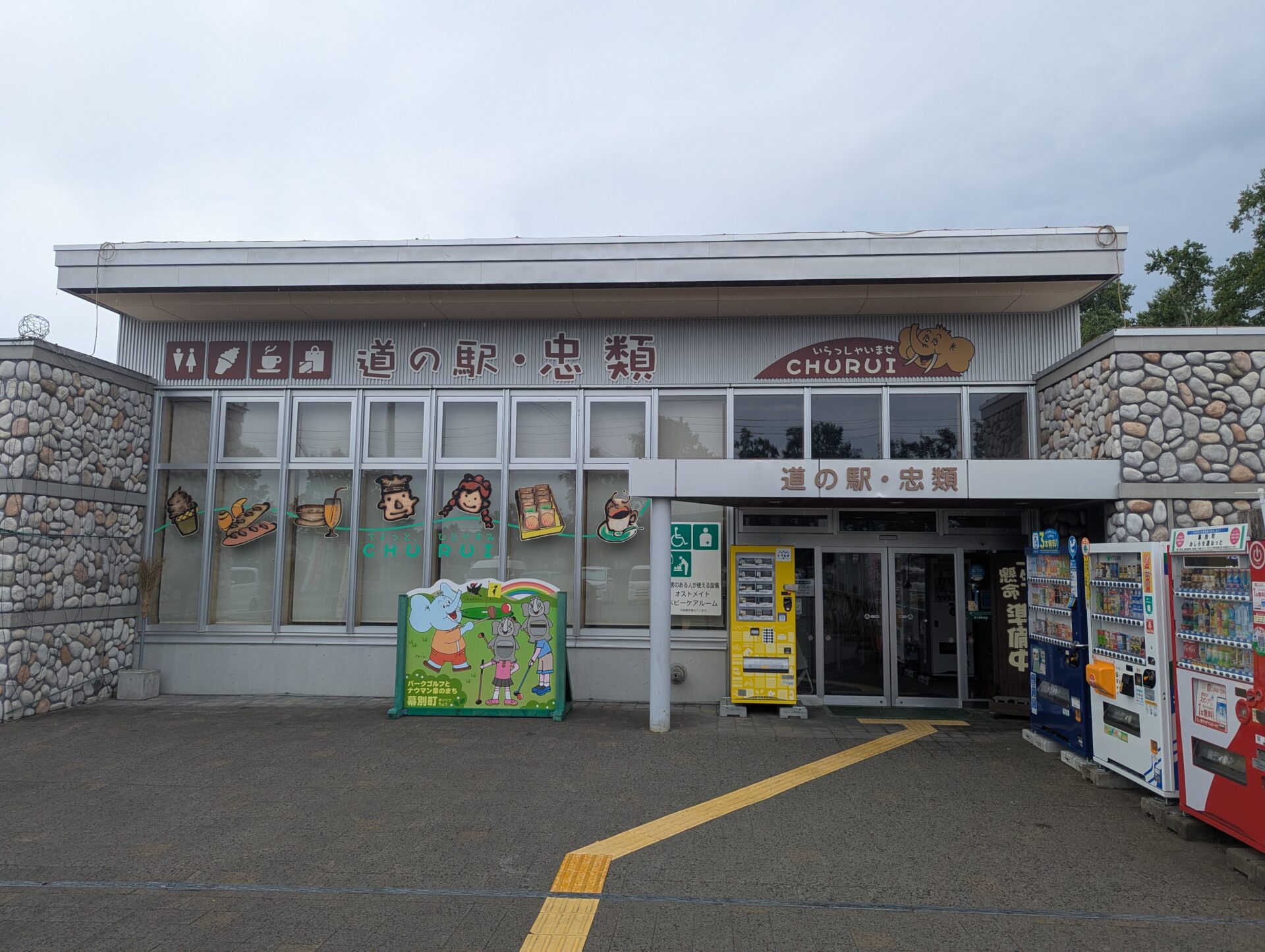 道の駅 忠類の正面入口、看板やキャラクターイラストが並ぶ建物