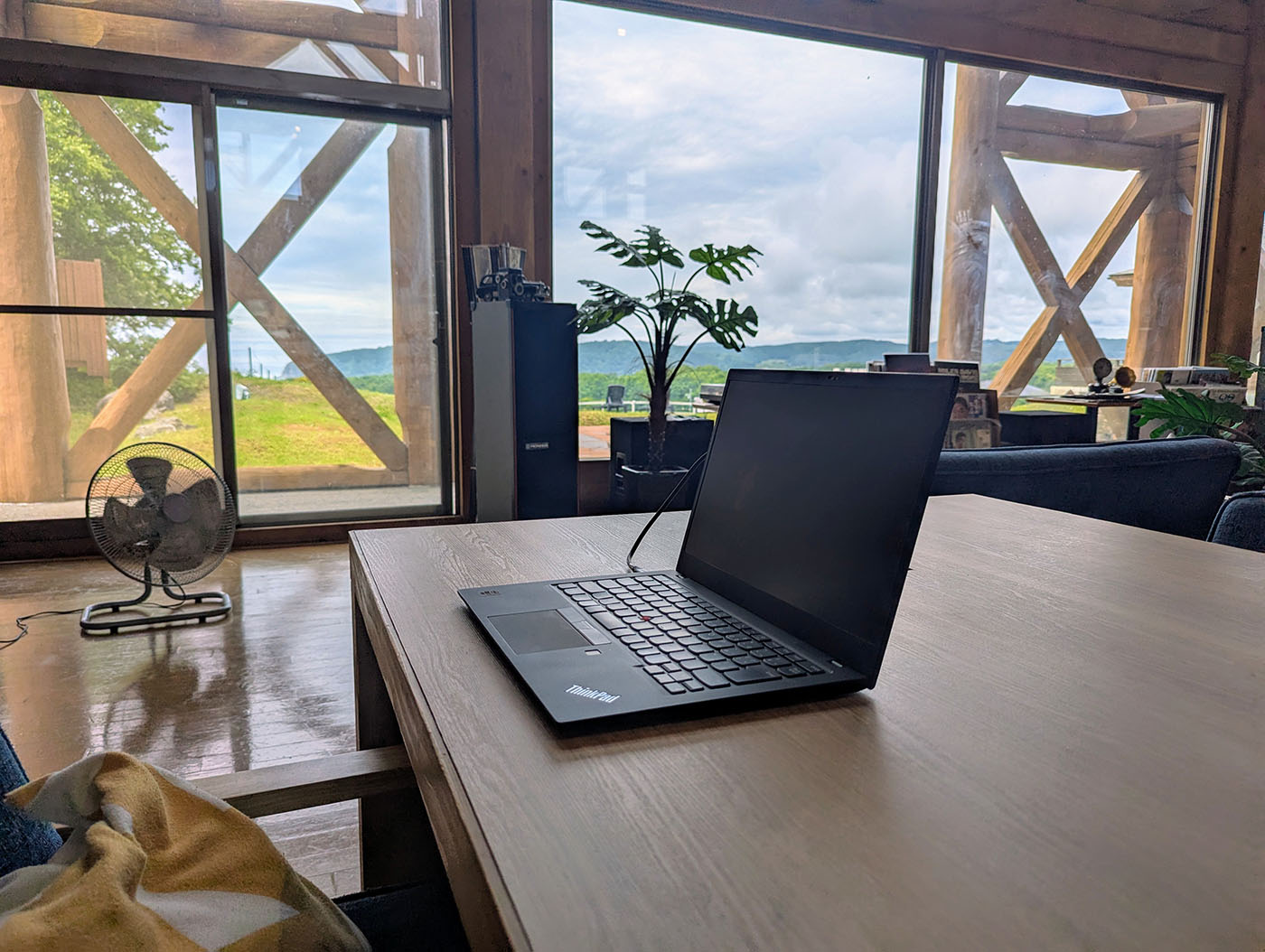 新冠温泉のテーブル席に置かれたノートパソコンと窓外の絶景