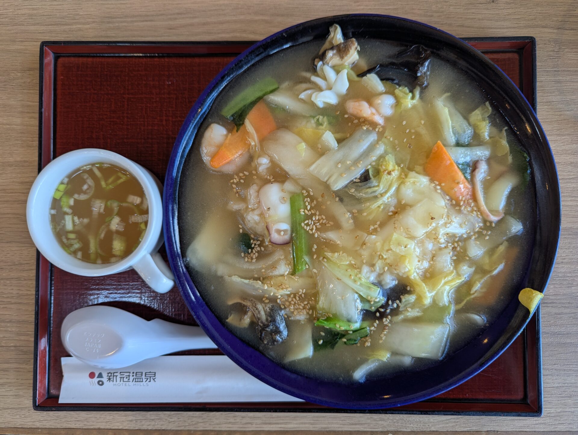 新冠温泉のレストランで注文したあんかけ海鮮飯。野菜と海鮮がたっぷり入ったとろみのある餡がご飯を覆い、香ばしい胡麻が散らされている。