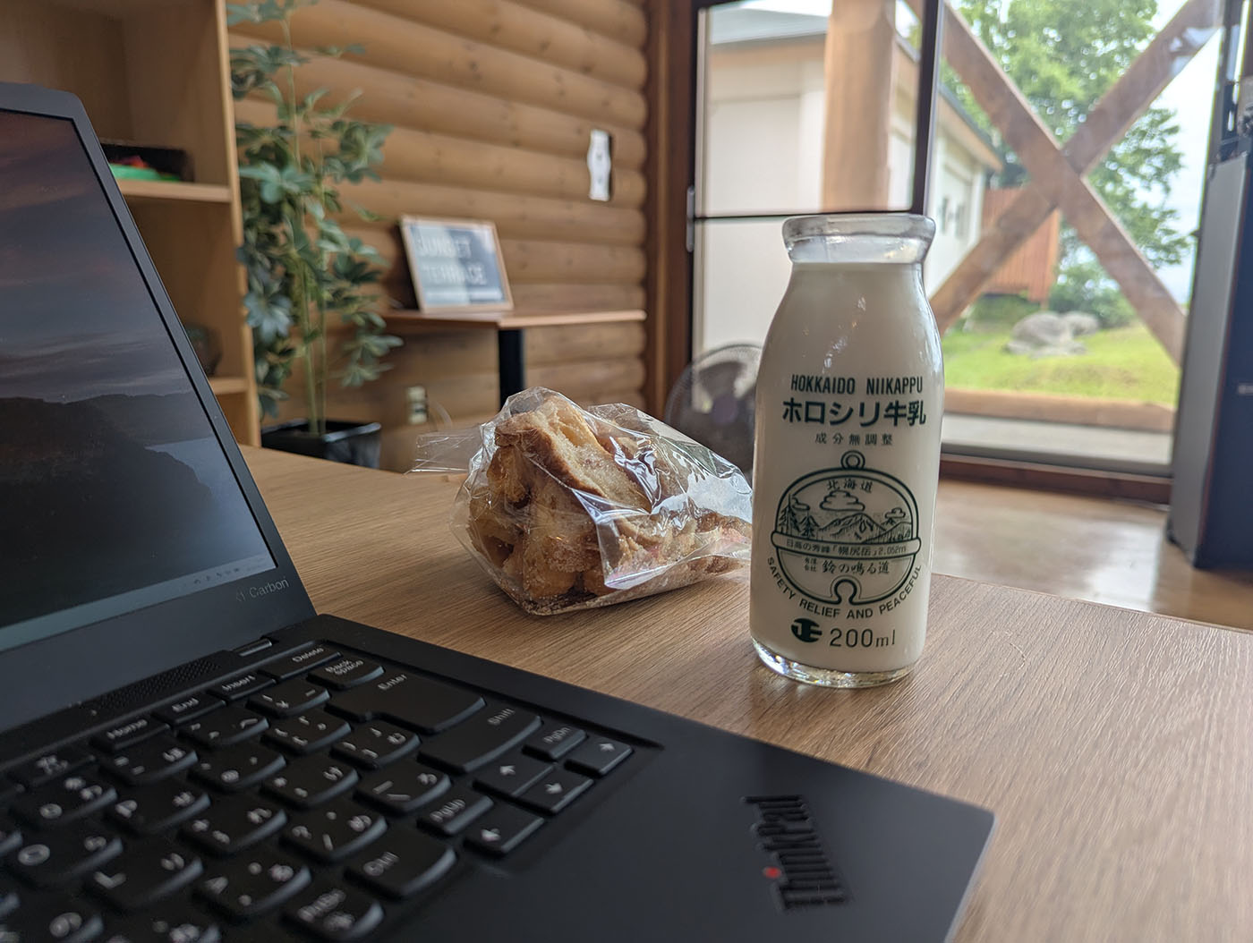 新冠温泉の休憩テーブルに置かれたホロシリ牛乳とクロワッサンラスク、ノートパソコン
