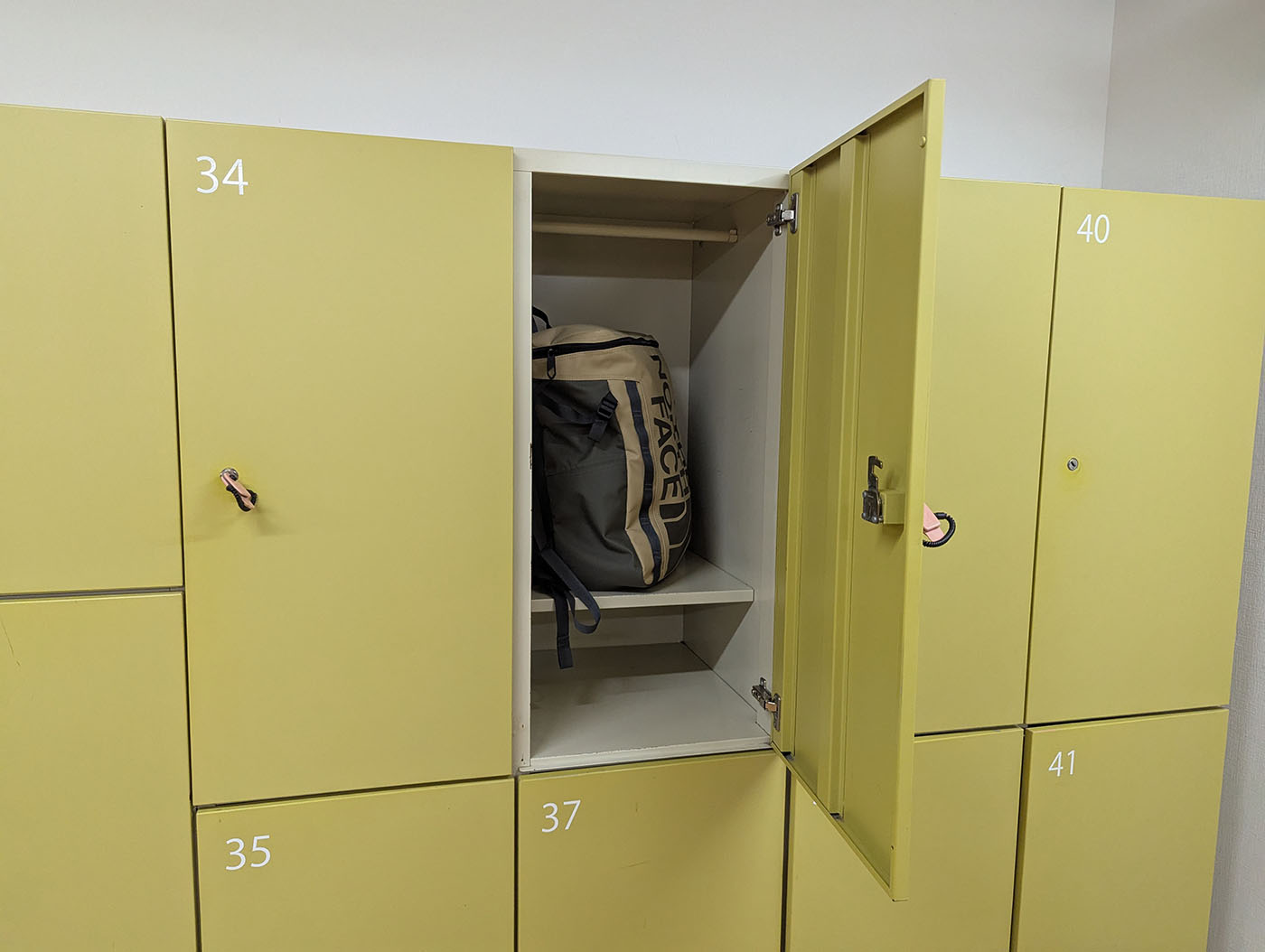 新冠温泉の脱衣所ロッカー。開いたロッカーの中に大きめのバックパックが収まっている