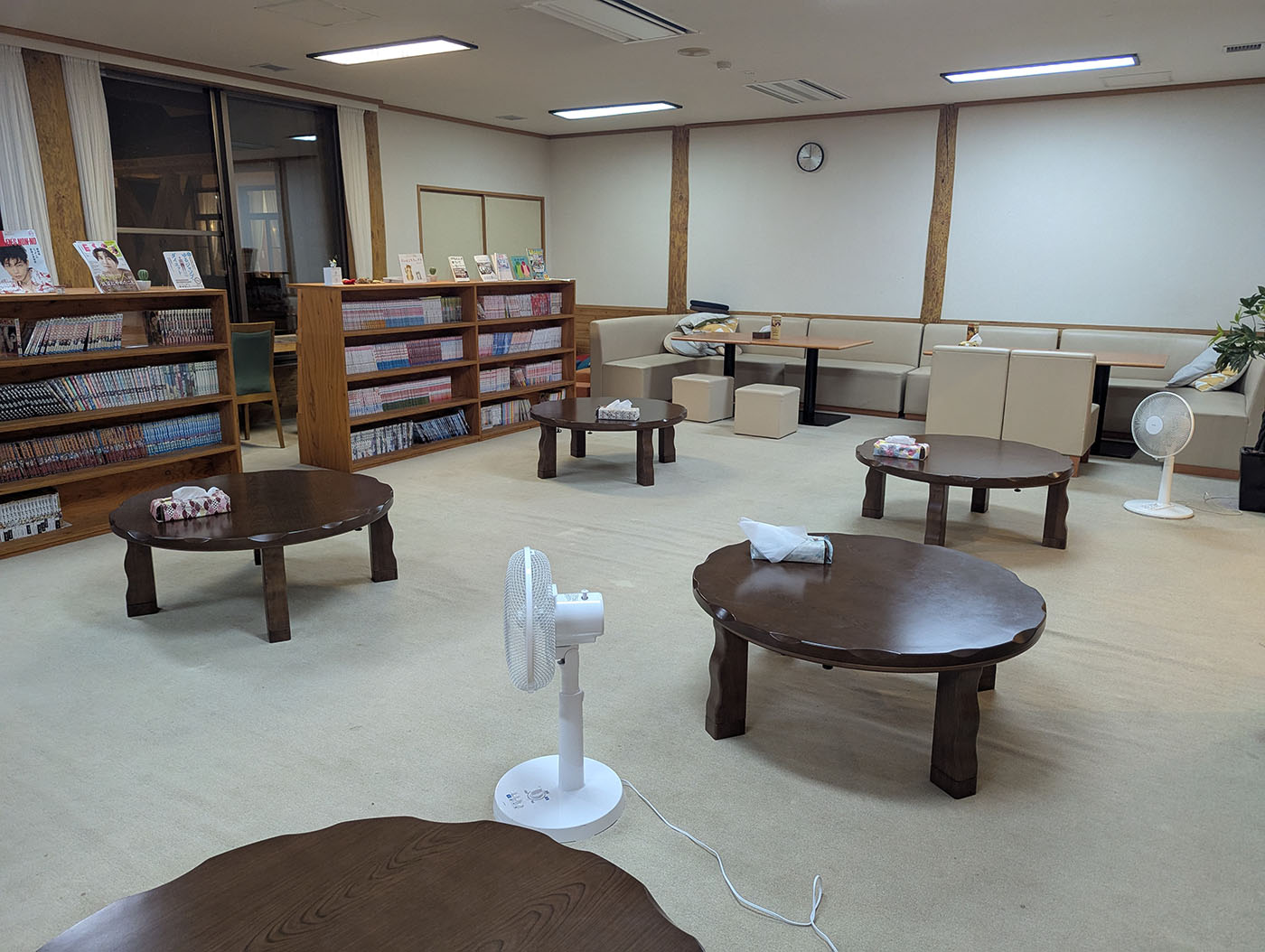 新冠温泉の休憩室。丸い座卓と本棚が並び、ゆったりとした空間が広がる