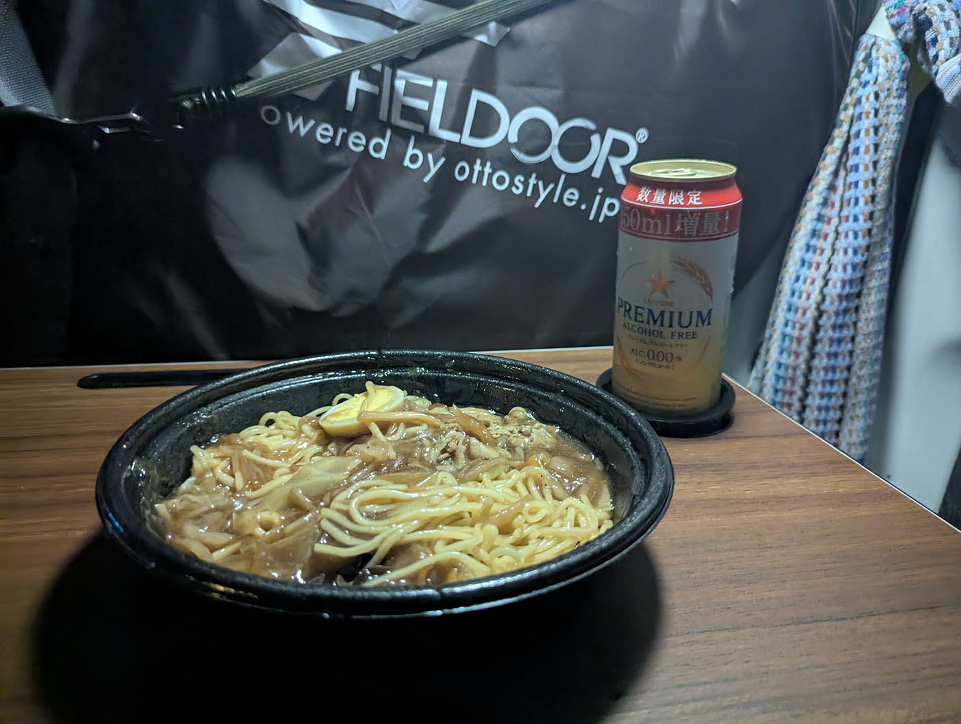 車内のテーブルに置かれたラーメンとノンアルコールビールの缶