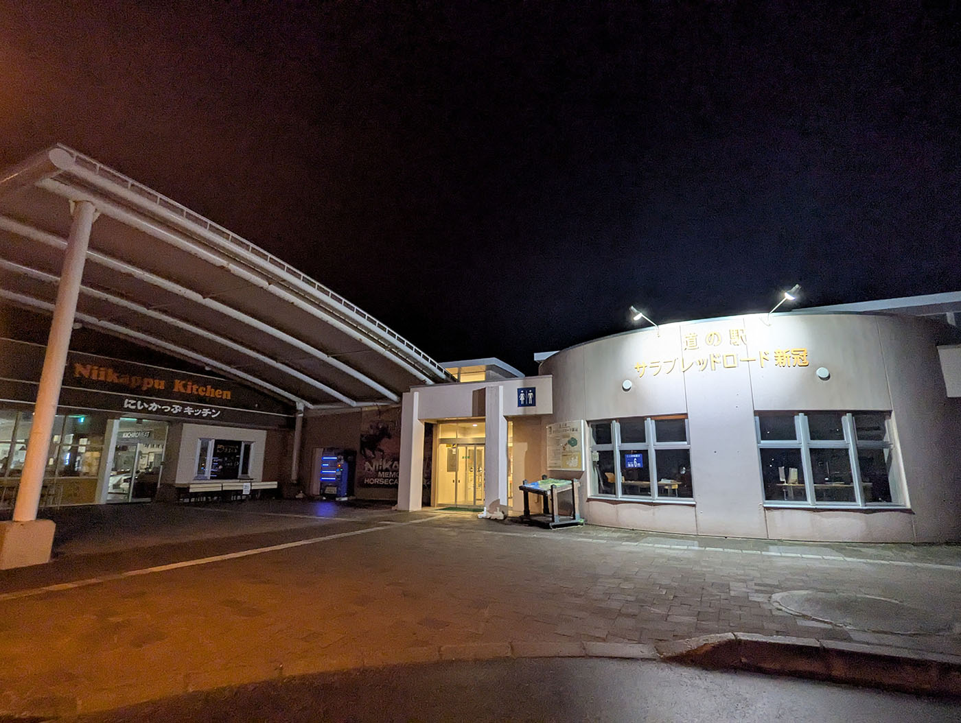 夜の道の駅サラブレッドロード新冠の外観、ライトに照らされた建物と看板