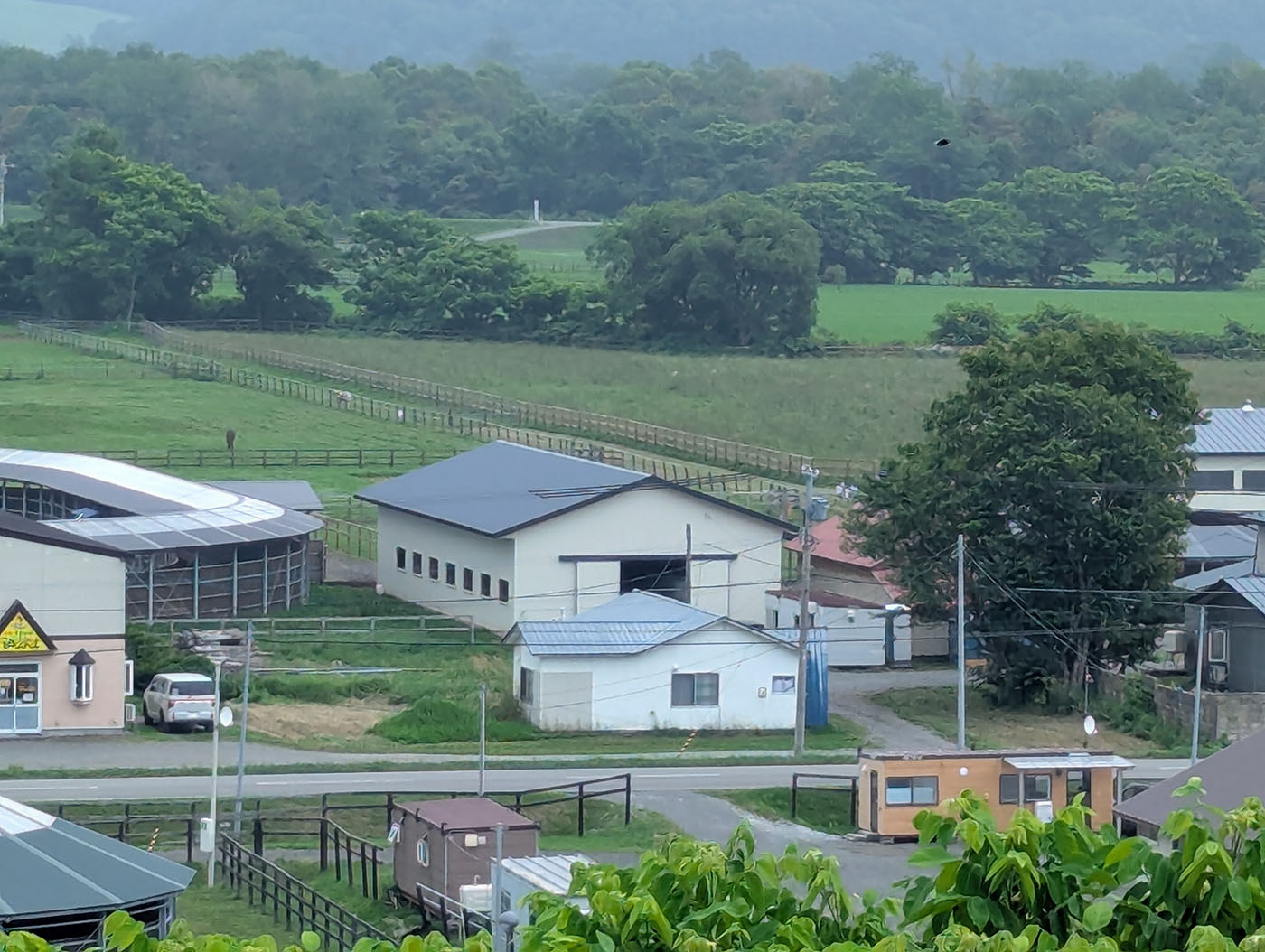 日高育成牧場の奥にある放牧地とトレーニング施設。遠くに馬の姿も見える。