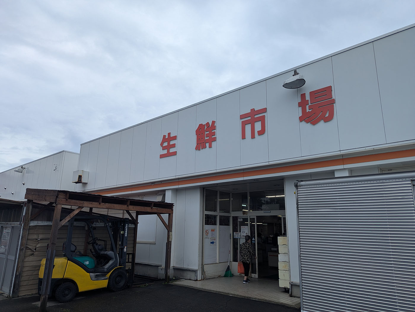 北海道の帯広にある生鮮市場の外観。フォークリフトが屋根付きスペースに停められ、市場の入り口には買い物客が出入りしている様子。