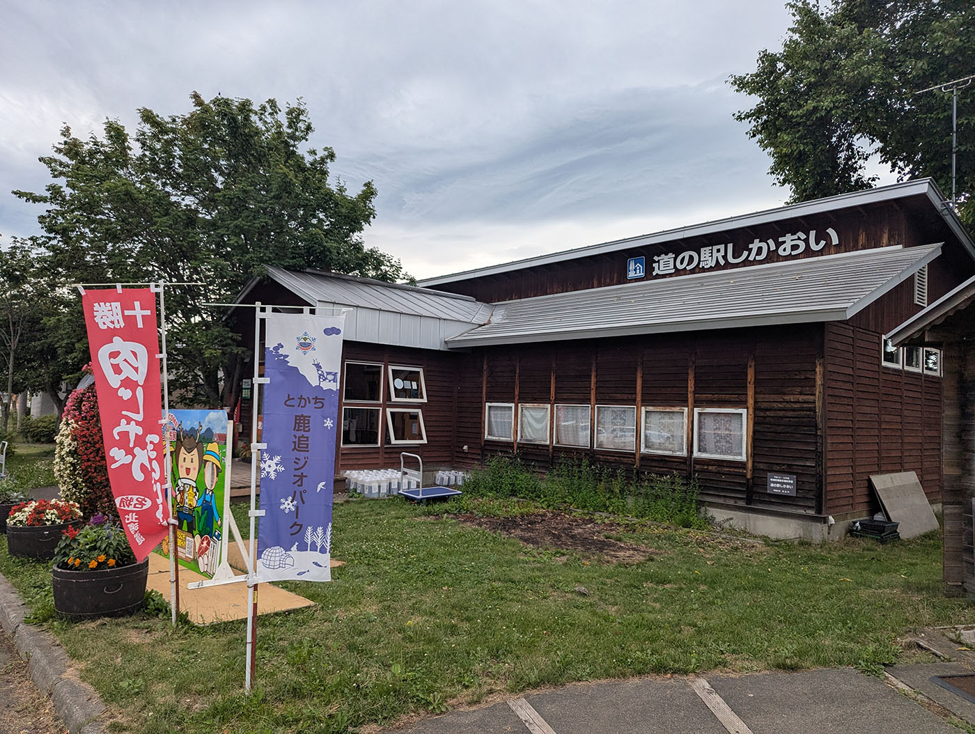 北海道鹿追町の「道の駅しかおい」の外観。木造の建物の前には「十勝肉サミット」や「とかち鹿追ジオパーク」の旗が立てられている。