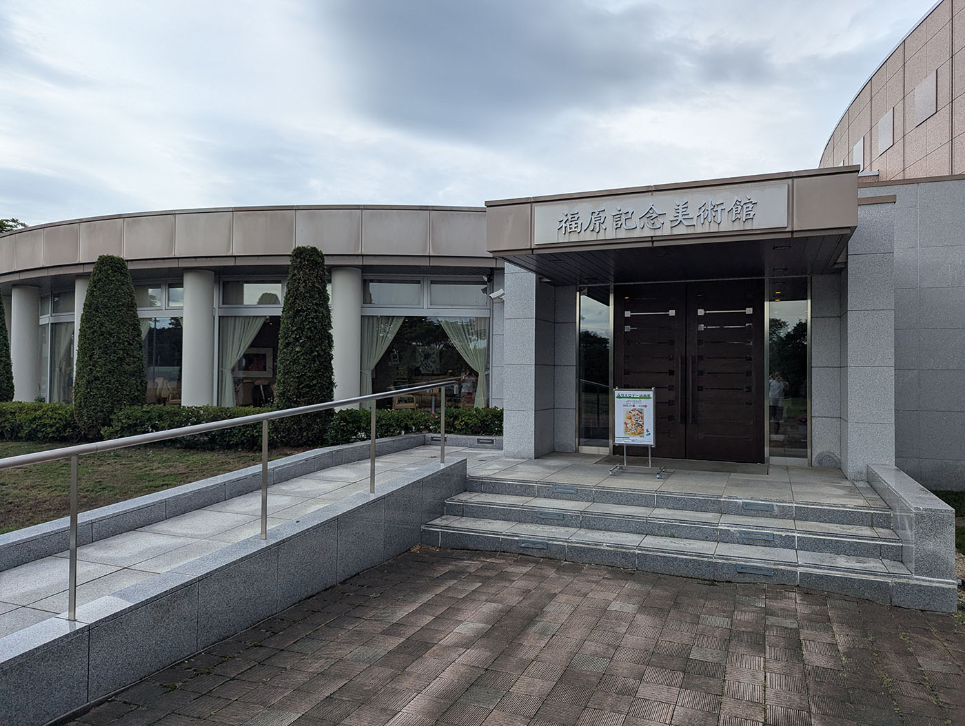 北海道鹿追町にある福原記念美術館の外観。曲線的なデザインが特徴の建物で、エントランスには花が飾られている。