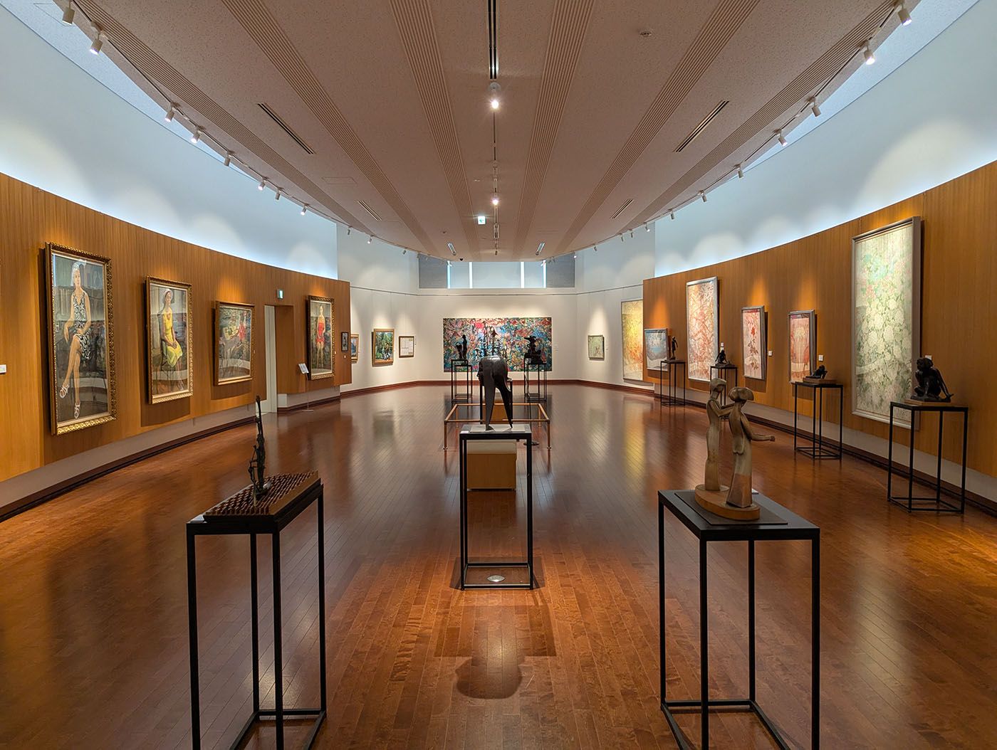 福原記念美術館の展示室内。木目調の床と壁に囲まれ、油彩画や彫刻が丁寧に配置された落ち着いた空間。