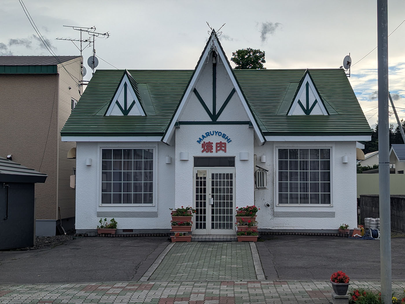北海道鹿追町にある焼肉店「MARUYOSHI 焼肉」の外観。白い壁と緑の屋根が特徴で、ヨーロッパ風の可愛らしい建物。