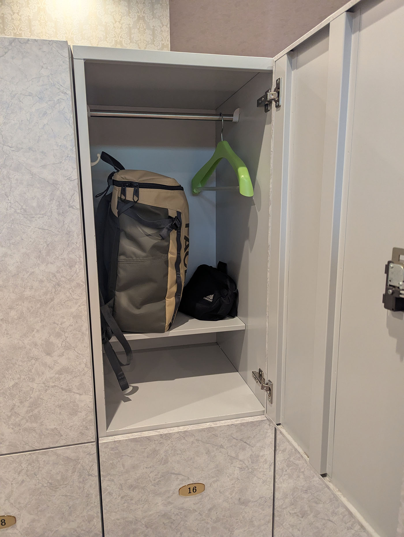 リュックが余裕で入るサイズのロッカー。緑色のハンガーと小物も収納されている。