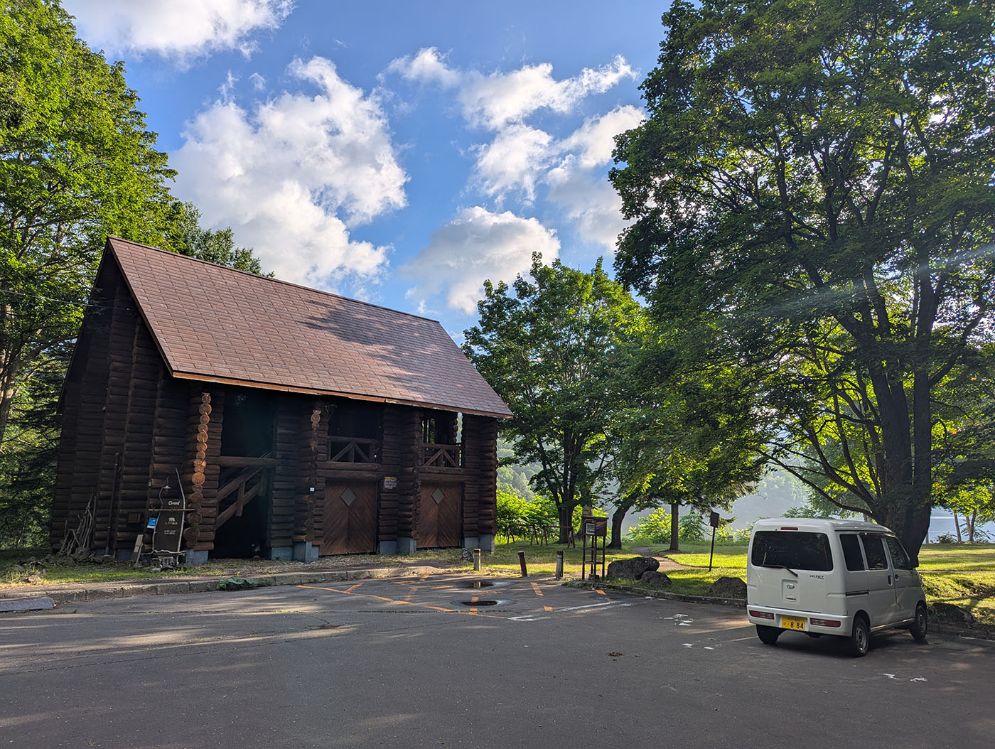 糠平湖駐車場とヒグマ珈琲の木造建物、白い軽バンが停まる朝の風景