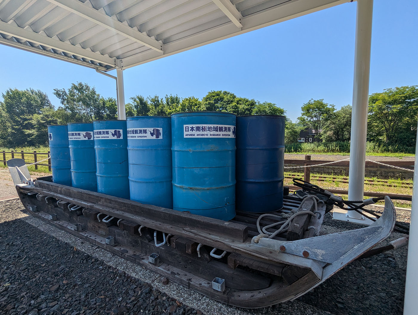 日本南極地域観測隊のロゴが貼られた燃料ドラム缶が整然と並ぶ橇の展示。