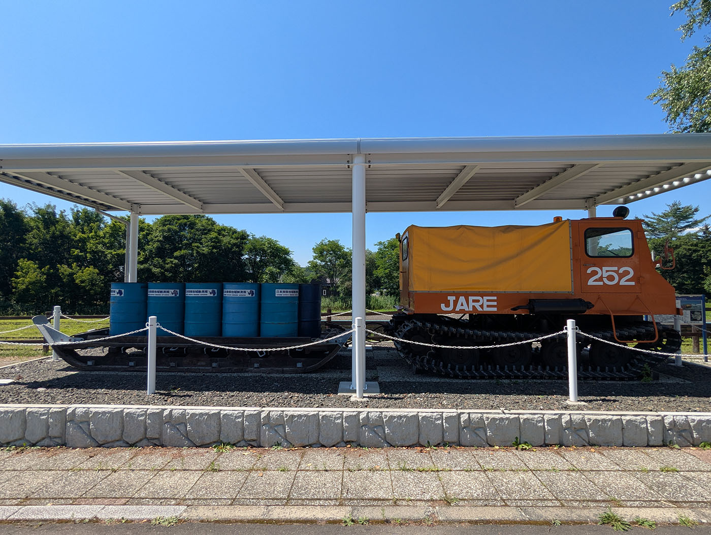 陸別町に展示されている南極観測用雪上車SM252と燃料ドラム缶。屋根付きの屋外展示。