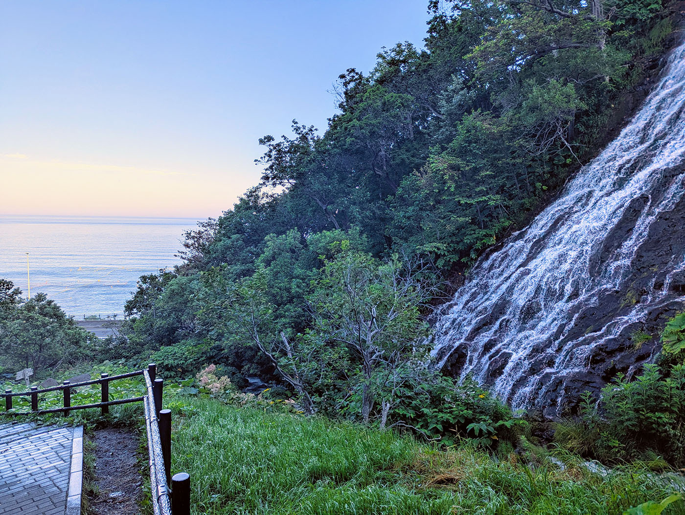 朝の光を受けるオシンコシンの滝とオホーツク海の眺め