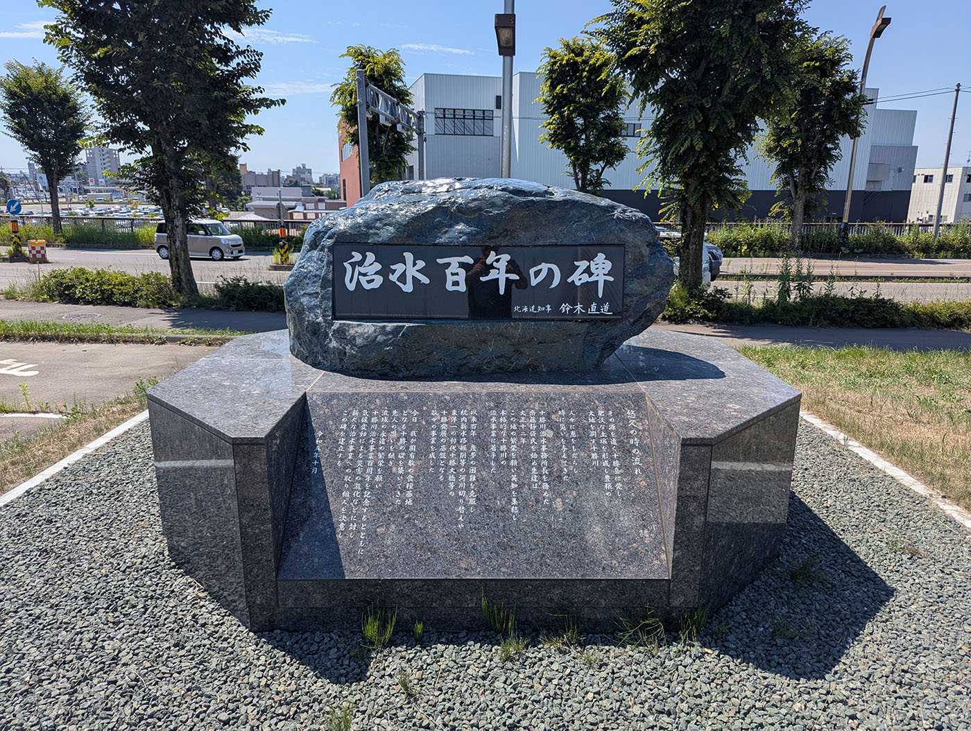「治水百年の碑」と題された記念碑。中央の大きな石に白い文字で銘が刻まれ、下部には解説文が彫られている。