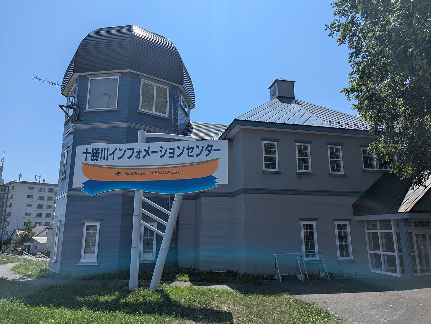 青空の下に建つ、青と白を基調とした洋館風の十勝川インフォメーションセンターの外観。