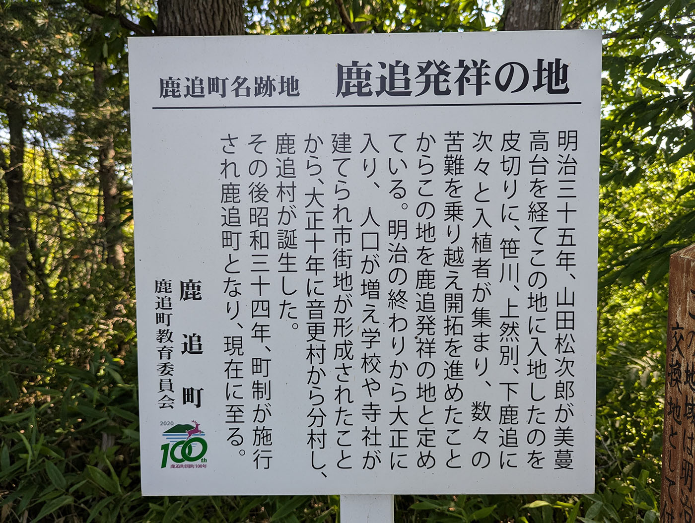 鹿追町の発祥に関する歴史を記した白い案内看板。明治から昭和にかけての町の歩みが記されている。
