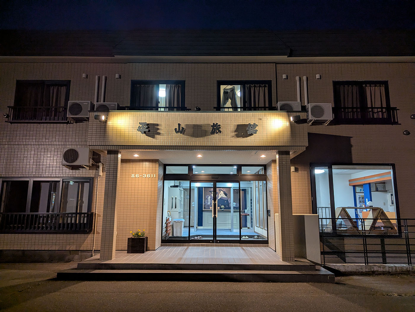 夕暮れ時にライトアップされた平山旅館の外観。