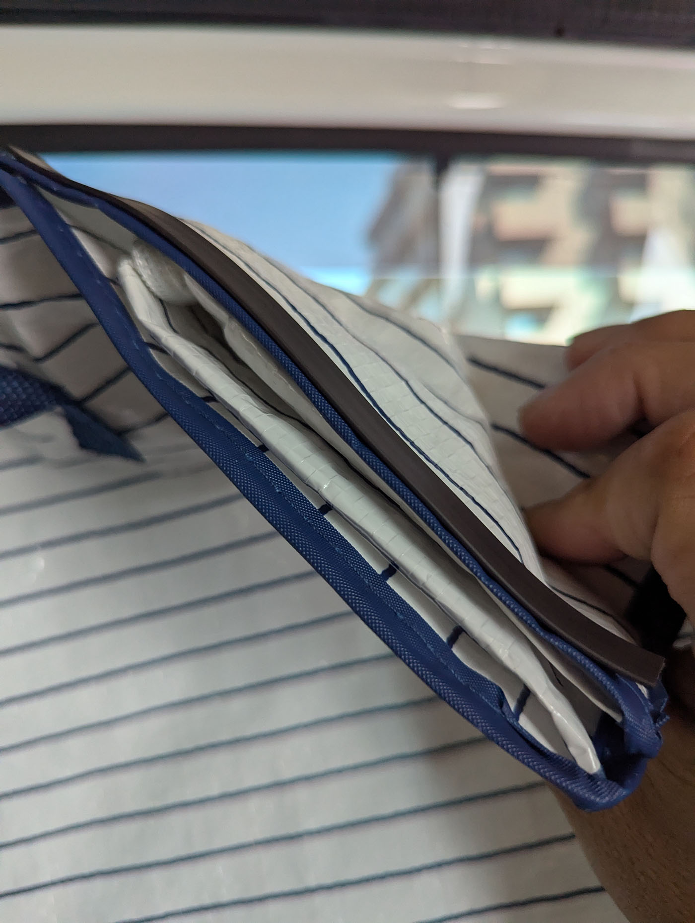 ランドリーバッグの上部にマグネットテープを貼り付けて遮光仕様に改良している様子の接写