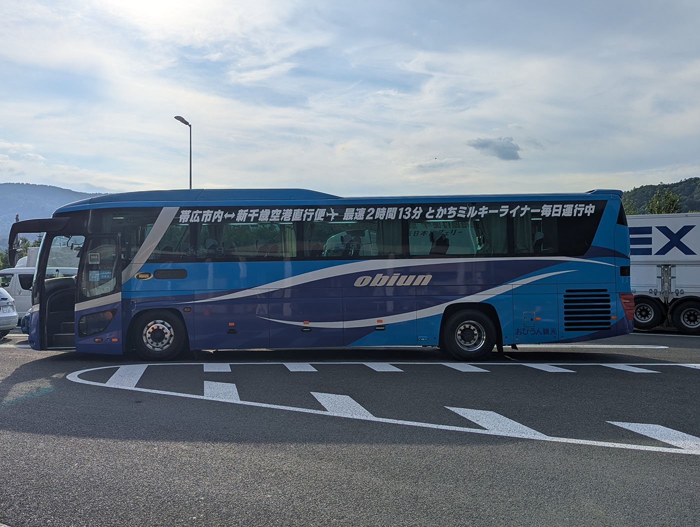 青と白の車体が特徴の長距離バス「ミルキーライナー」が、帯広から新千歳空港へ向かう途中の休憩所で停車している様子。