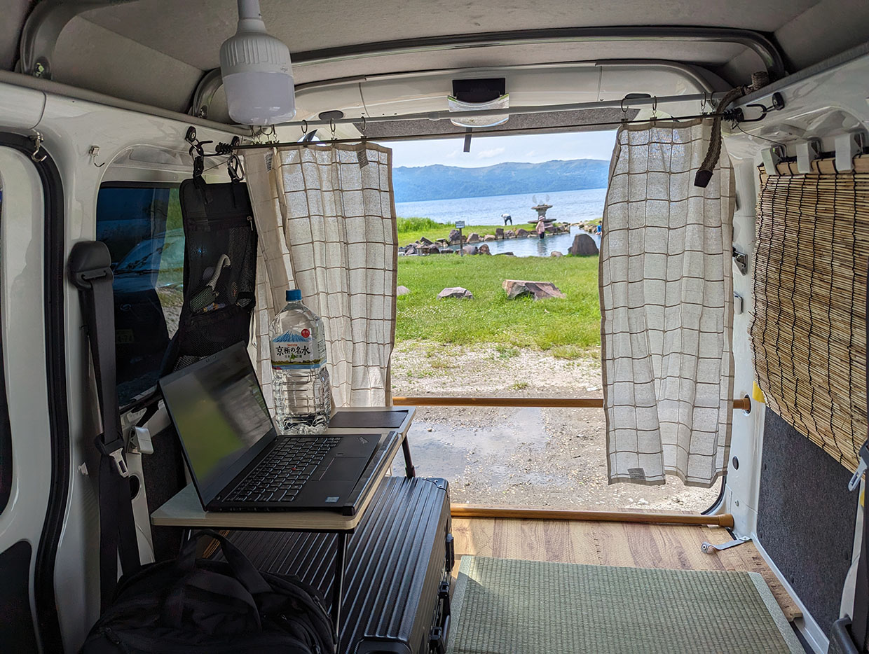 ハイゼットカーゴの荷室をワークスペースにして、屈斜路湖の湖畔を眺めながらノマドワークする様子