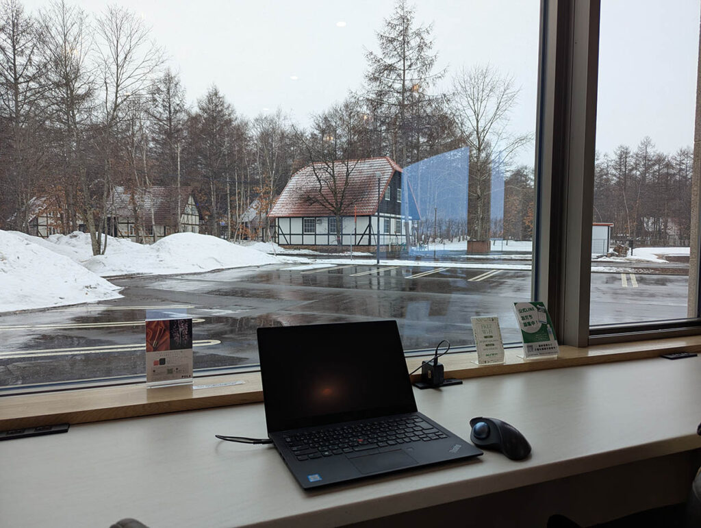 十勝エアポートスパそらの窓際カウンターでノートPCを広げ、雪景色を眺めながら仕事をするノマドワーク環境