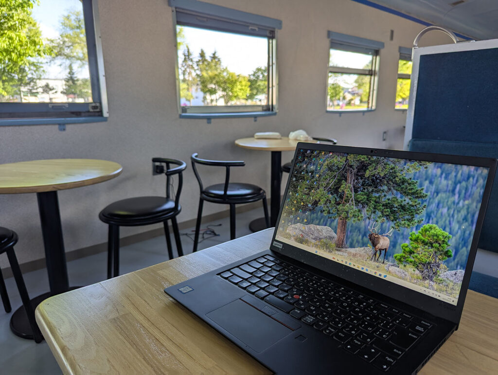 おこっぺ町の廃車両を利用した休憩スペースでノートPCを広げ、レトロな鉄道空間をワークデスクに変えた様子