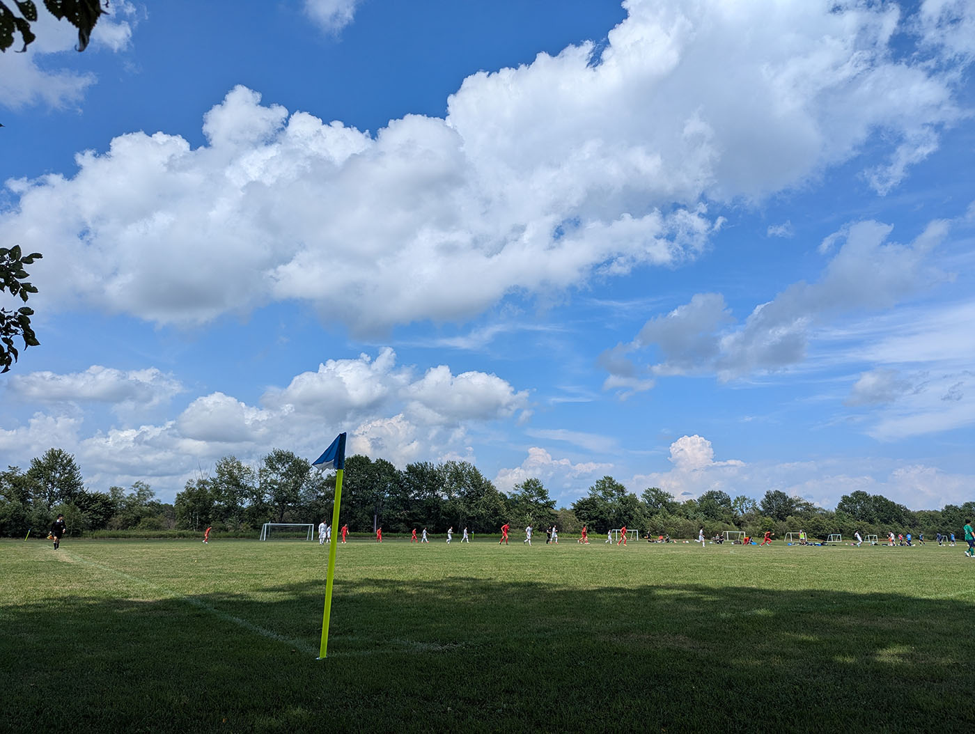 十勝川河川敷のサッカーグラウンドで試合をする子どもたちと青空に映えるコーナーフラッグ