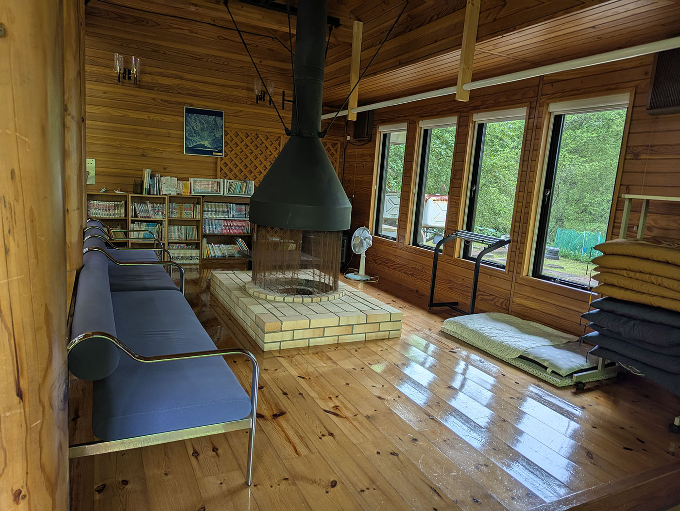 達古武オートキャンプ場の管理棟内部、暖炉とソファが並ぶ休憩スペース。達古武オートキャンプ場の管理棟。漫画や本もあり、暖炉を囲んでくつろげる空間